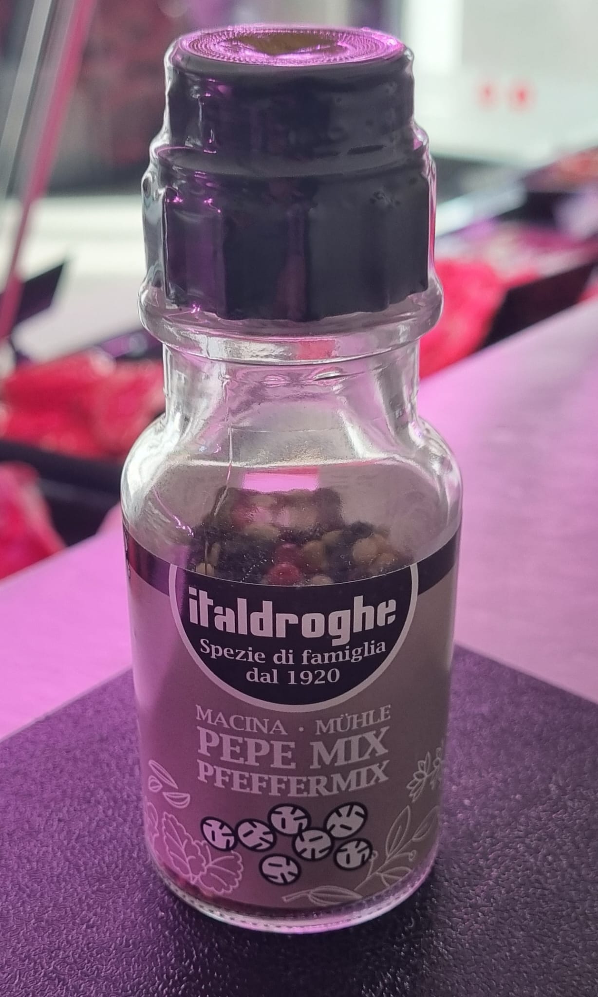 Bottle of Pepe Mix featuring black, white, green, and pink peppercorns, ideal for enhancing various dishes.