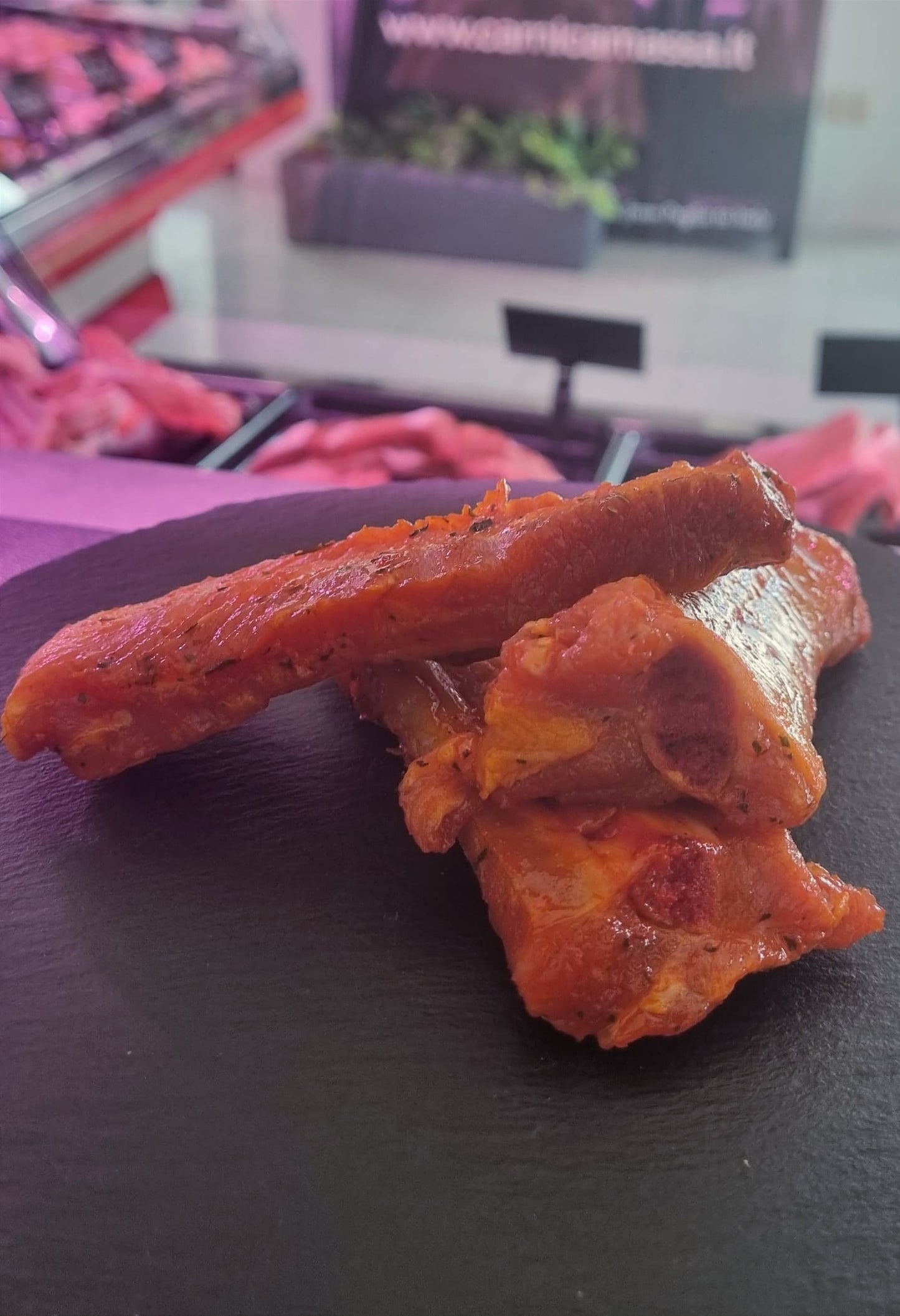 Costine di maiale in salsa barbecue su un piatto nero, pronte per essere servite. Perfette per barbecue e forno.