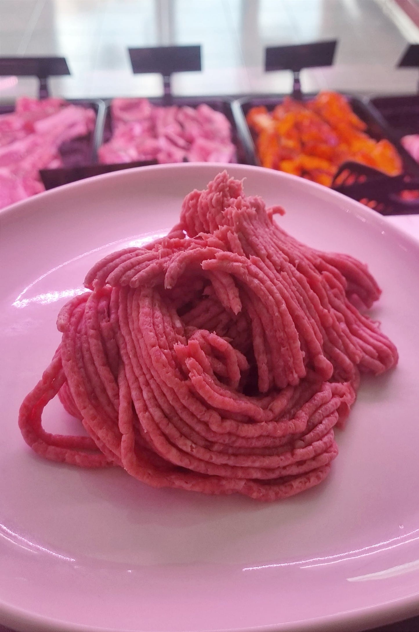 Tritato di bovino fresco su piatto, ideale per polpette, hamburger e altre ricette.