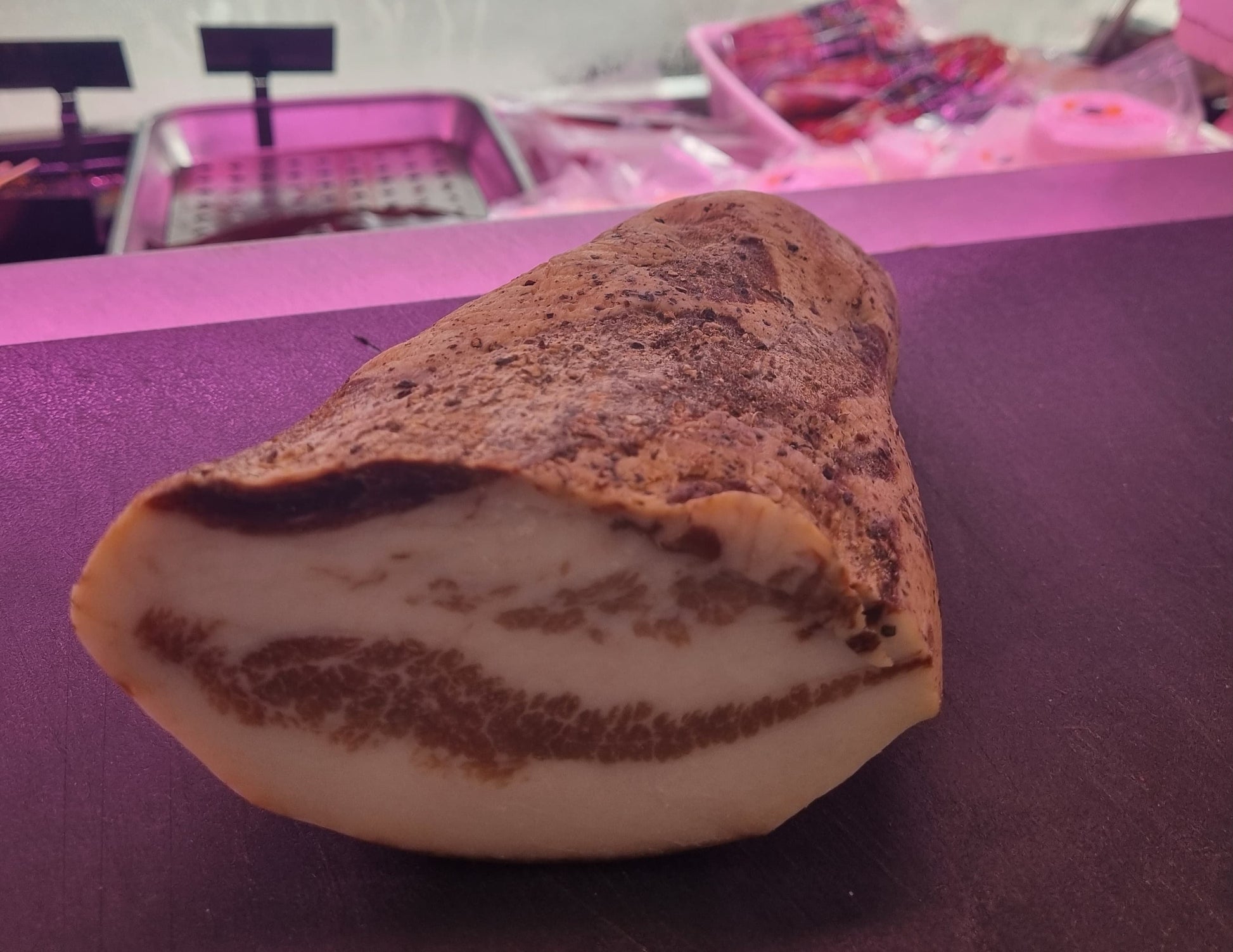 Guanciale affumicato tagliato, mostra strati di grasso e carne, pronto per essere gustato.